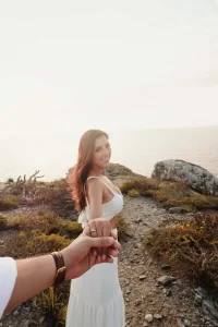Girl posing at the beach with guy holding her hand