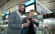 Travelers using a smartphone and holding boarding passes inside an airport terminal