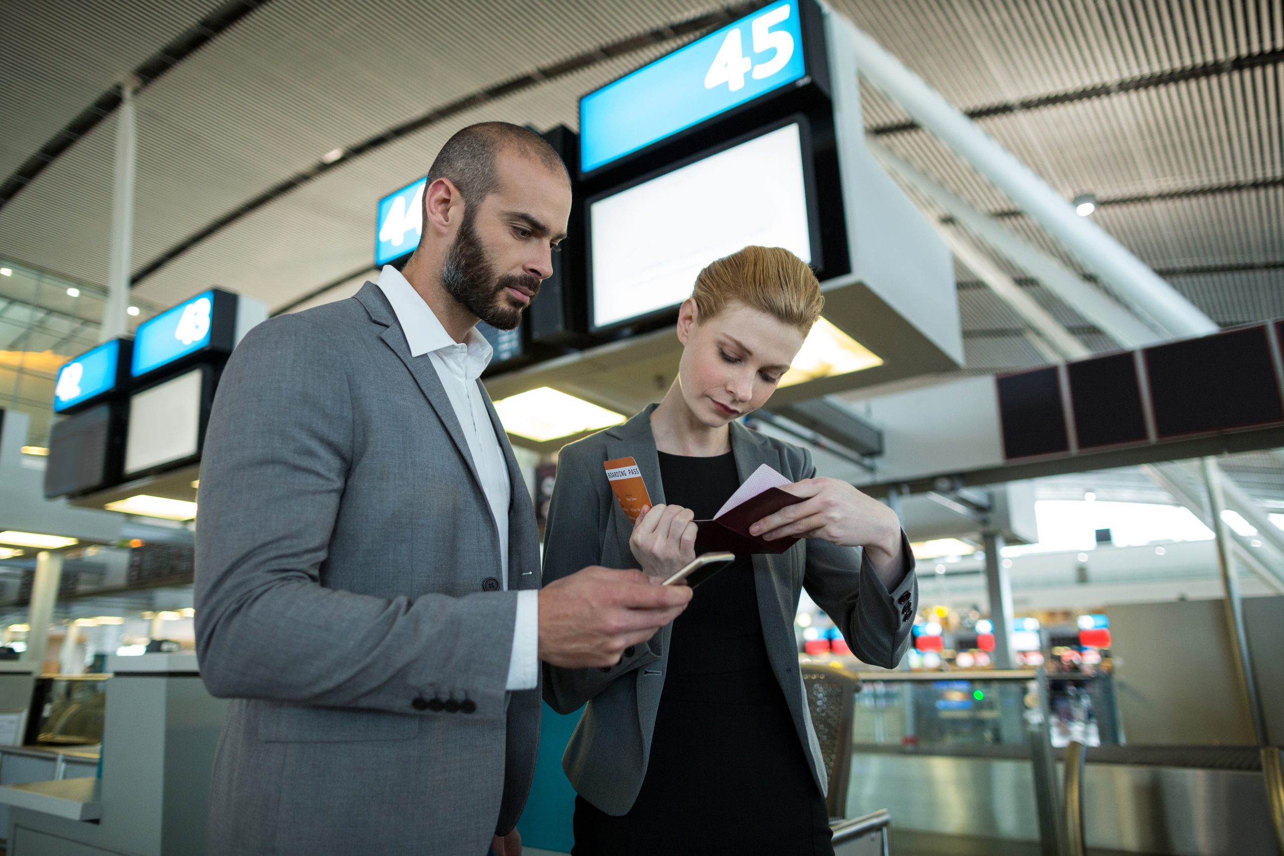 Travelers using a phone and boarding passes inside an airport terminal