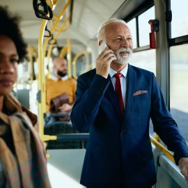 Passenger riding an airport terminal shuttle while checking connection details by phone