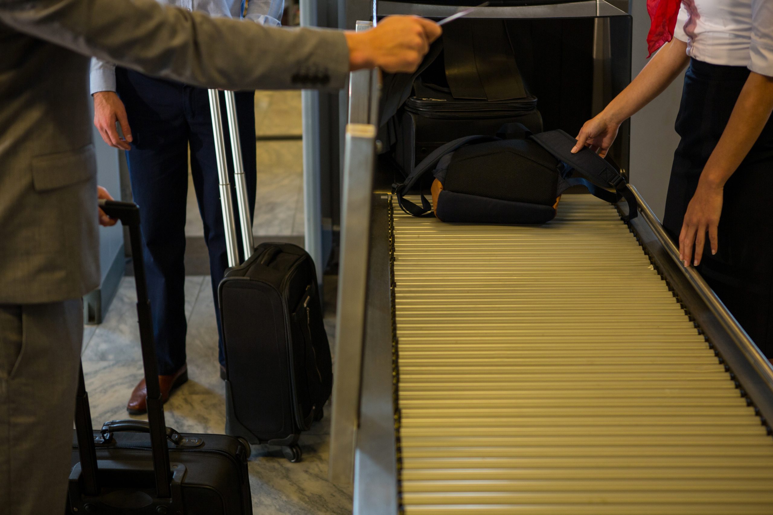 Airport staff assisting passengers with checked luggage on a conveyor belt