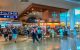 Travelers passing shops and departure-gate signs inside Cancun Airport